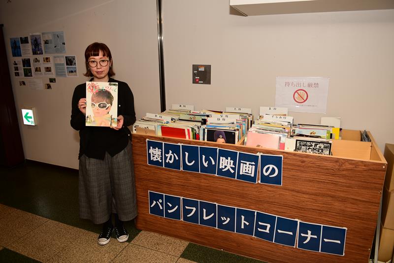 館内の映画パンフレットコーナーを紹介する山田さん。パンフレットは全て客からの寄付品=柏市