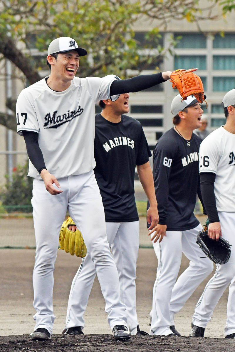 春季キャンプでの守備練習中に笑顔を見せる千葉ロッテの佐々木朗希(左)=4日、沖縄県石垣市