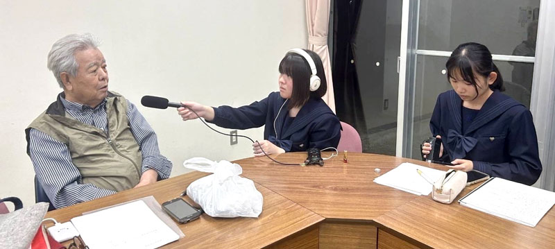 福田村事件追悼慰霊碑保存会代表の市川さん（左）を取材する柏南高放送部の生徒たち（同校放送部提供）