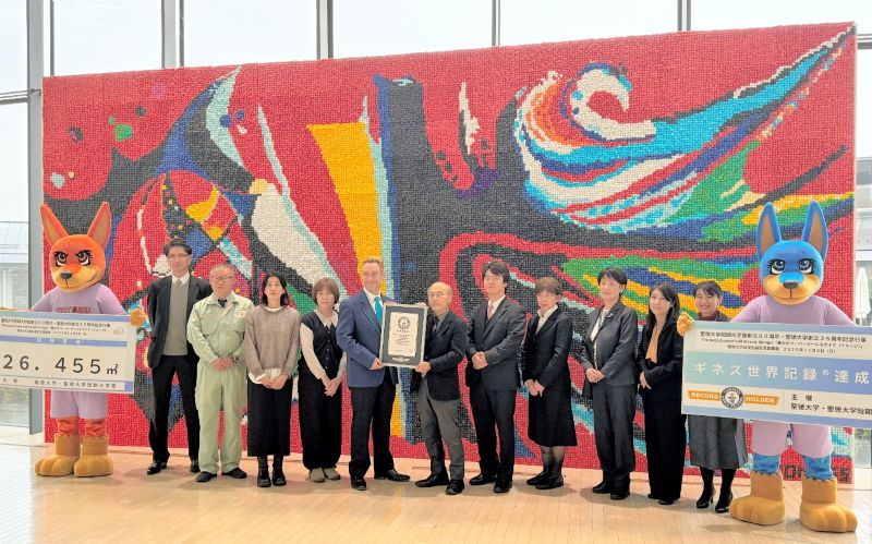 「最大のペーパーボールモザイク（イメージ）」としてギネス世界記録に認定された作品を背に、記念撮影する聖徳大・短期大学部の関係者ら＝９日、松戸市