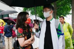 　「高考」の受験会場前でチャイナドレス姿の保護者（左）と話す受験生＝７日、北京（共同）