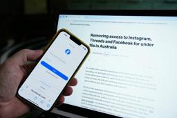 　フェイスブックのログイン画面と、新たなメタの方針が映し出されたモニター＝２０日、オーストラリア・シドニー（ＡＰ＝共同）