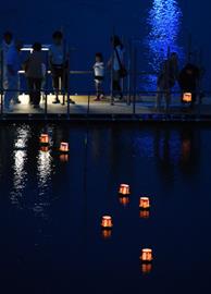 小糸川に浮かぶ灯籠の明かりが夏の夕暮れを彩った＝１６日、君津市中野