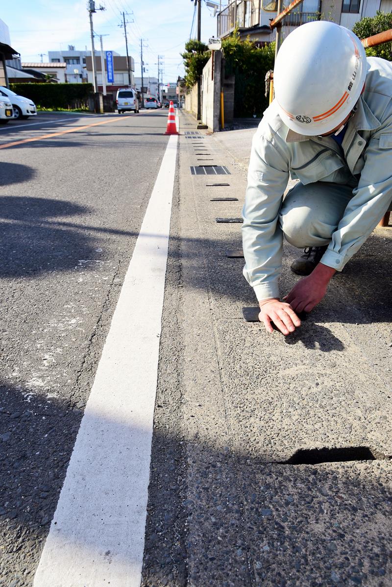 寄付を受け、側溝の穴にカバーを取り付ける館山市職員(同市提供)