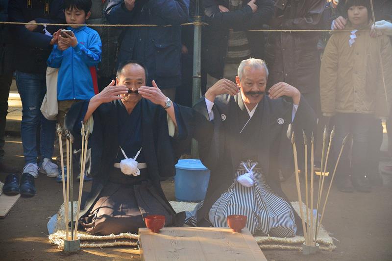 ひげをなでて新当番に酒を勧める旧当番＝１３日、香取市の側高神社