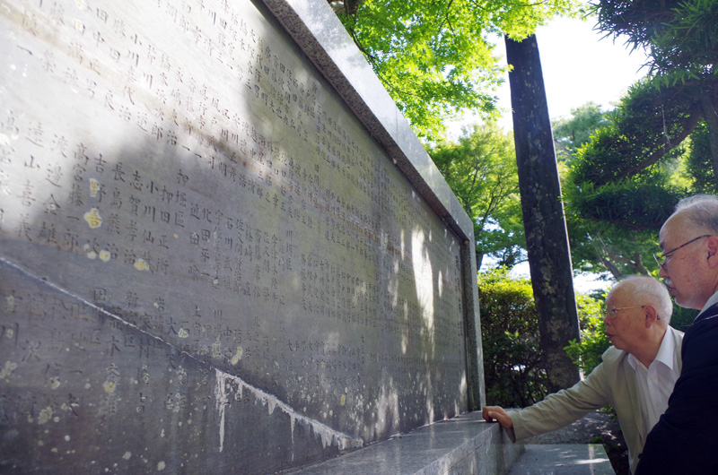 旧東金町が1952年に建立した縦120センチ・横296センチの「戦没英霊」の碑には満州事変から太平洋戦争までの276人の戦没者名が地域別に記載されている。碑文で戦禍を振り返る木村会長(左)と宇野さん=東金市の八鶴湖畔専有地