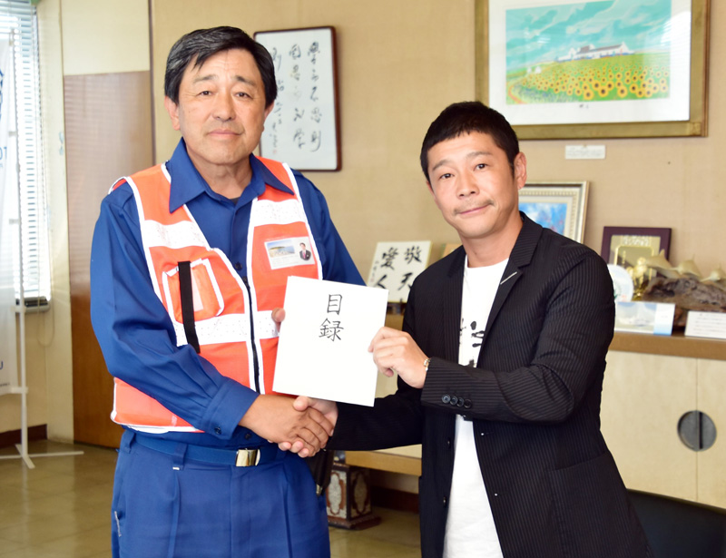 館山市の金丸謙一市長(左)に目録を手渡す前澤さん(同市提供)