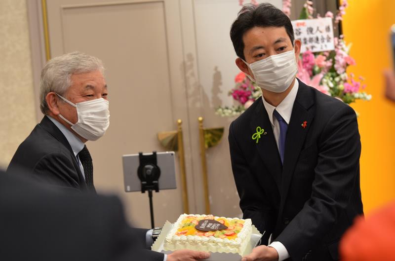 当選祝いのケーキを受け取る熊谷氏（右）＝２１日夜、千葉市中央区のホテル