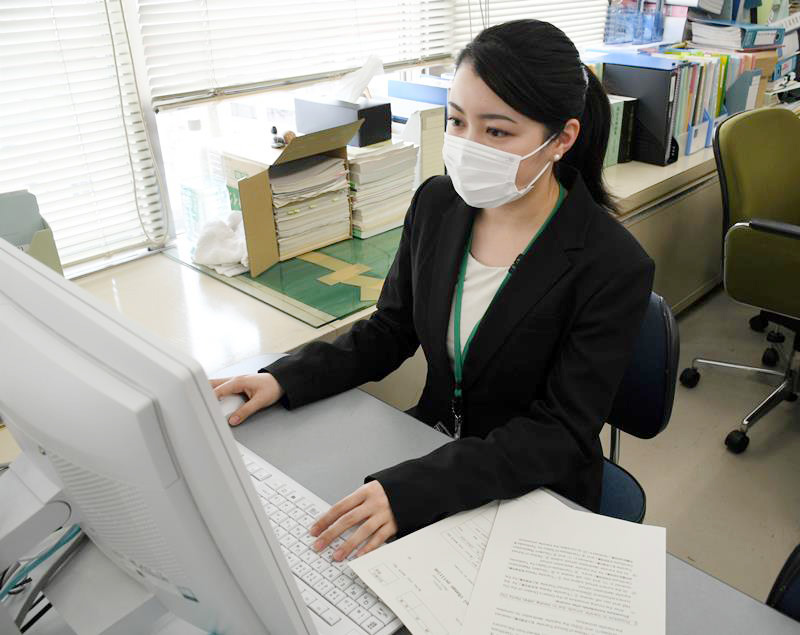 英訳された手続き書類を確認しながらデスク業務するＪＡＬスカイの谷口さん＝成田市役所