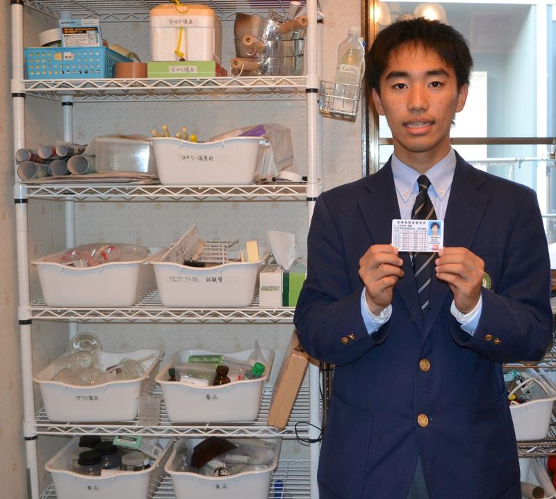 自室にある実験道具の横で、危険物取扱者免状を手にする小早志さん