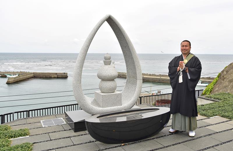 海洋葬「海の弔い」の供養塔前で手を合わせる妙海寺の佐々木住職＝勝浦市