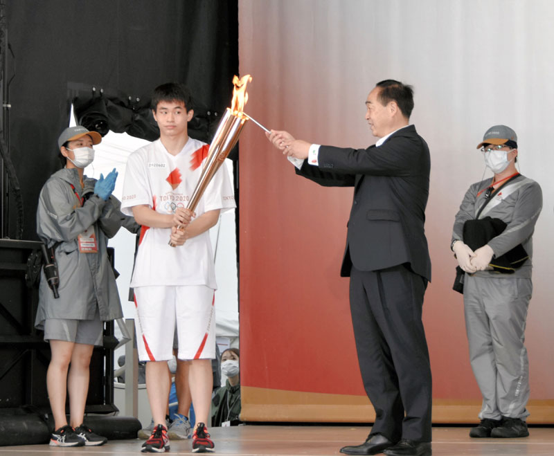 山武市の松下浩明市長（右）からトーチに火を灯される錦織孟徳さん