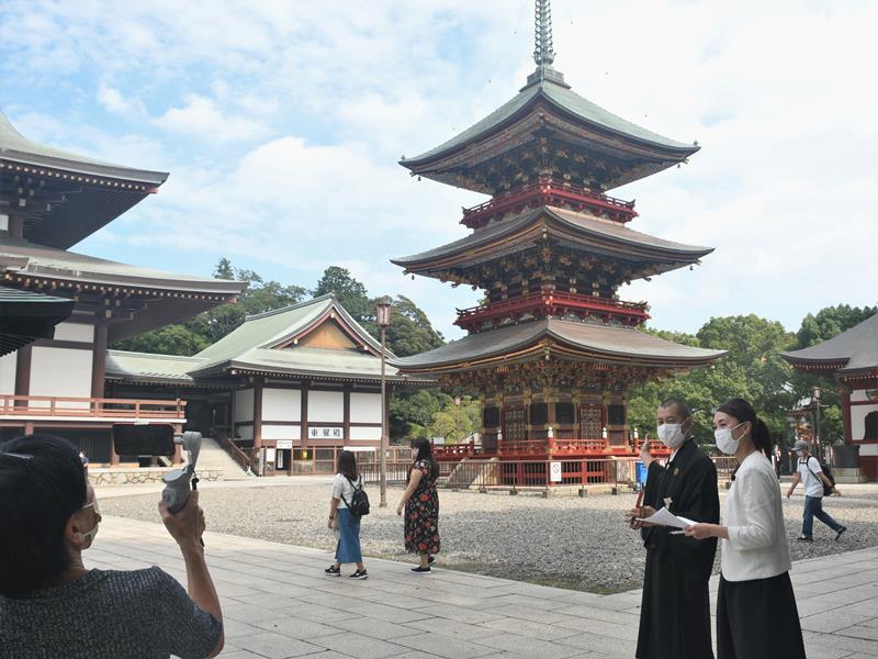 スマートフォンで中継し、リアルタイムの成田山新勝寺の様子を伝えた＝成田市