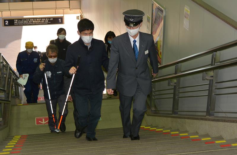 白杖を使う視覚障害者の階段の上り下りについて対応を学ぶ北総線の駅員