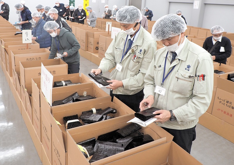 初競りに出品される新ノリの色つや、香りを確認する業者ら＝２７日、富津市