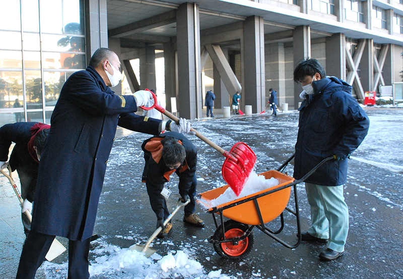 県庁前で雪かきをする県職員。午前６時半ごろから作業を始めた＝７日午前９時ごろ、千葉市中央区