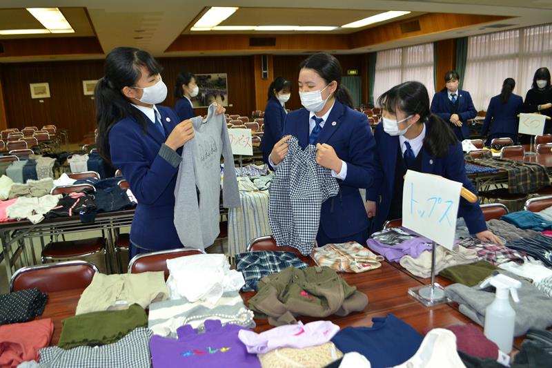 回収された古着を前に、友人と品定めする県立千葉女子高の生徒ら=19日、千葉市稲毛区