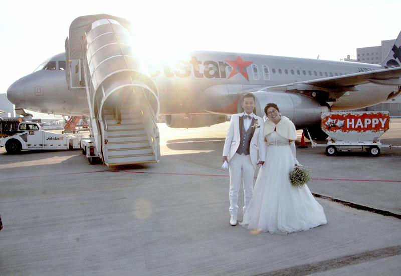 「空の上の結婚式」を前に、チャーター便の前で記念撮影＝成田空港