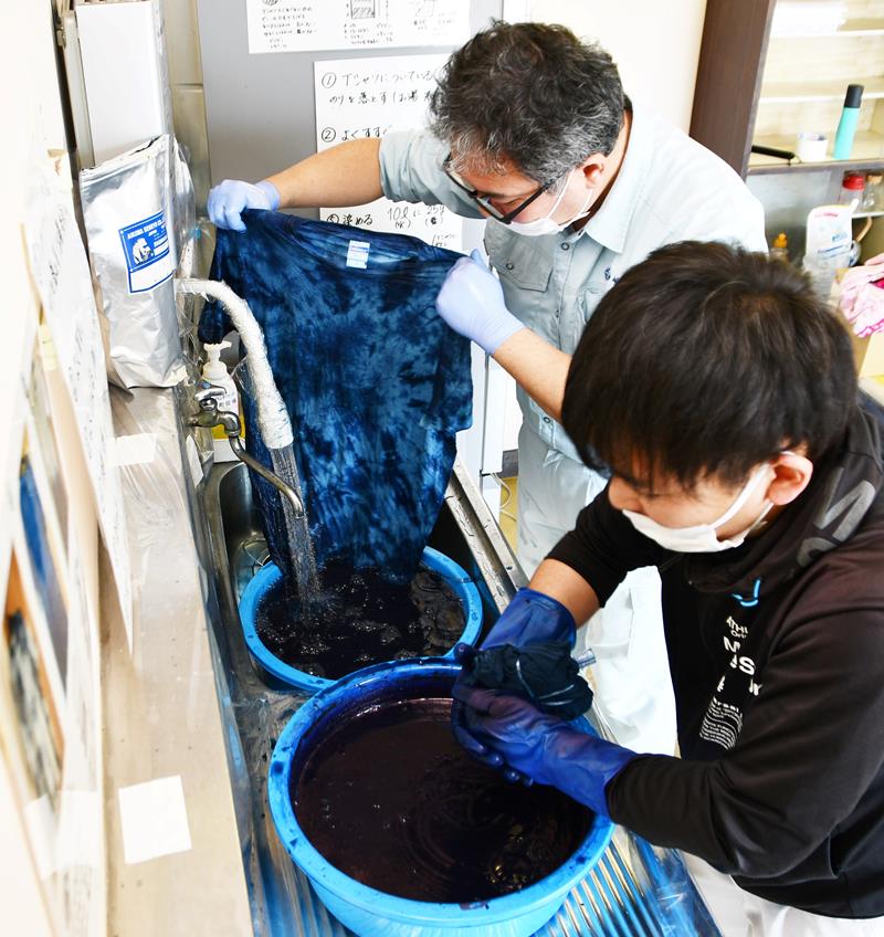 白色のシャツ一枚一枚を丁寧に藍染めする町職員＝９日、神崎町