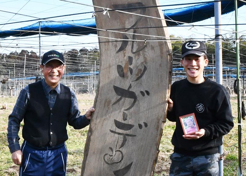 大熊の直売所で使用していた看板と一緒に笑顔を浮かべる元樹さん（右）と好一さん＝香取市