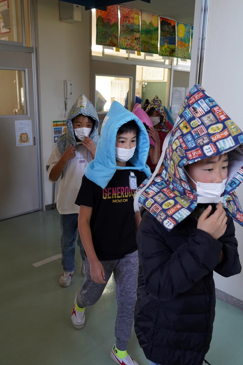 防災頭巾をかぶって避難する児童=11日、いすみ市立古沢小