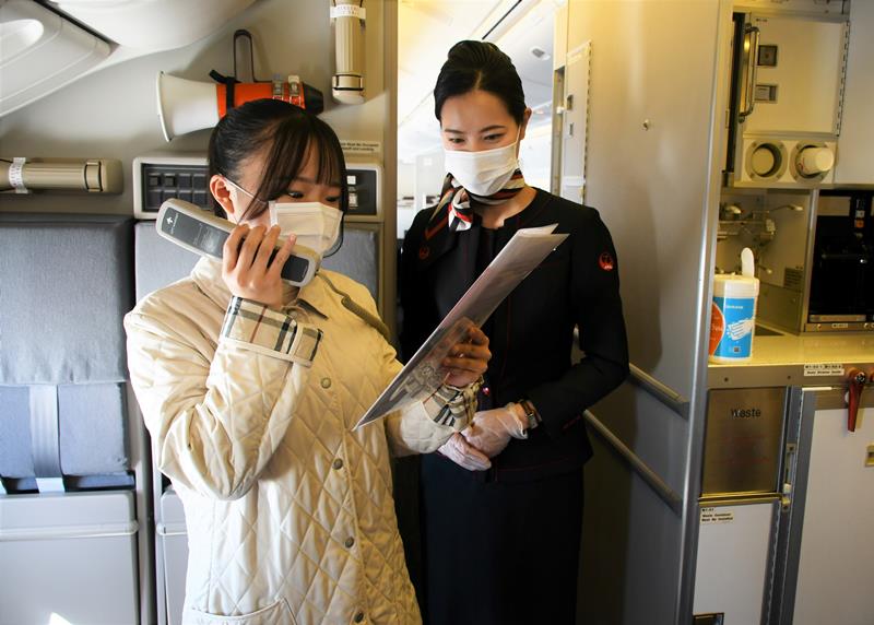 フライト中の機内でアナウンスを体験する高校生