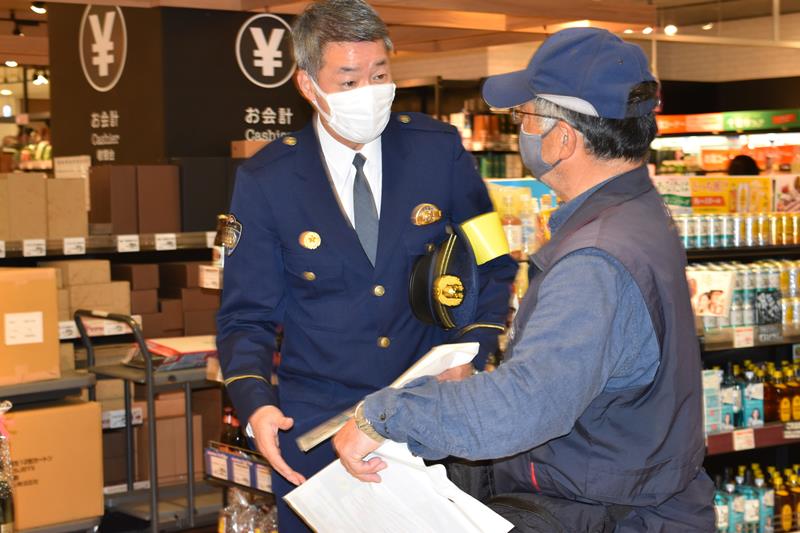来店客にパンフレットなどを配布する松木生活安全部長＝１５日午前、千葉市緑区の「ゆみ～る鎌取ショッピングセンター」