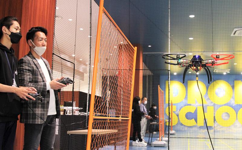 ドローンスクールの屋内コートで操縦する後藤社長（左から２人目）＝千葉市美浜区