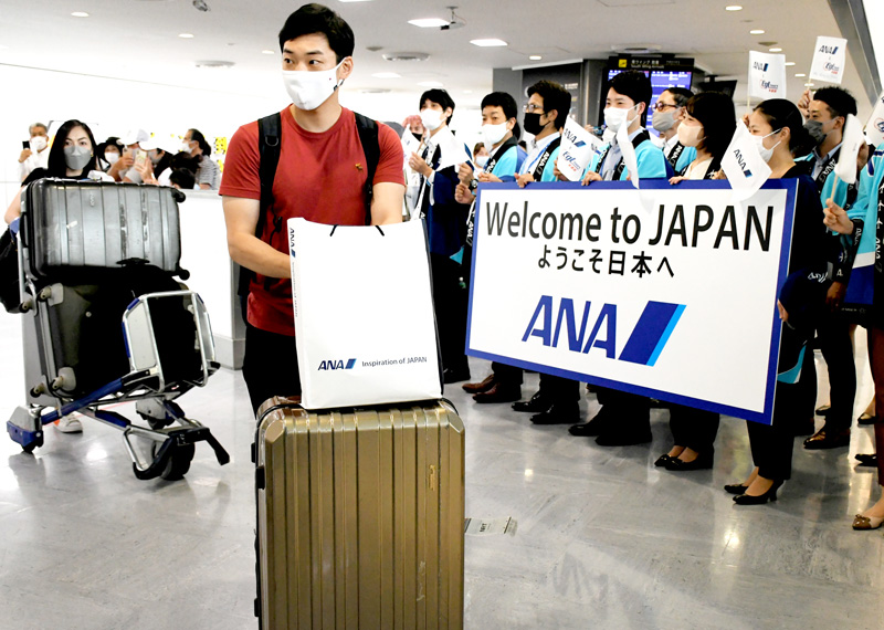 ２年以上ぶりに日本に訪れた香港からのツアー客。航空会社や旅行会社のスタッフが到着ロビーで歓迎した＝２２日、成田空港