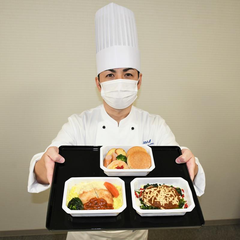 成田ならではの返礼品として用意された機内食セットのハンバーグや白身魚フライを紹介する末シェフ=成田市