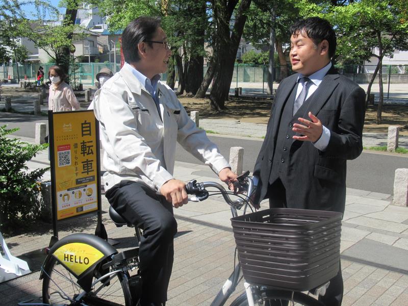 オープンストリートの工藤社長（右）から、シェアサイクルの説明を受ける田中市長＝１６日、市川市の全日警ホール前で