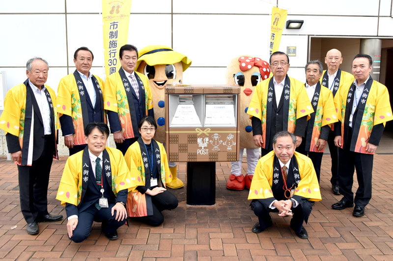 ＪＲ八街駅南口に設置されたラッピングポスト。前列左から２人目がデザインした市職員の深谷さん