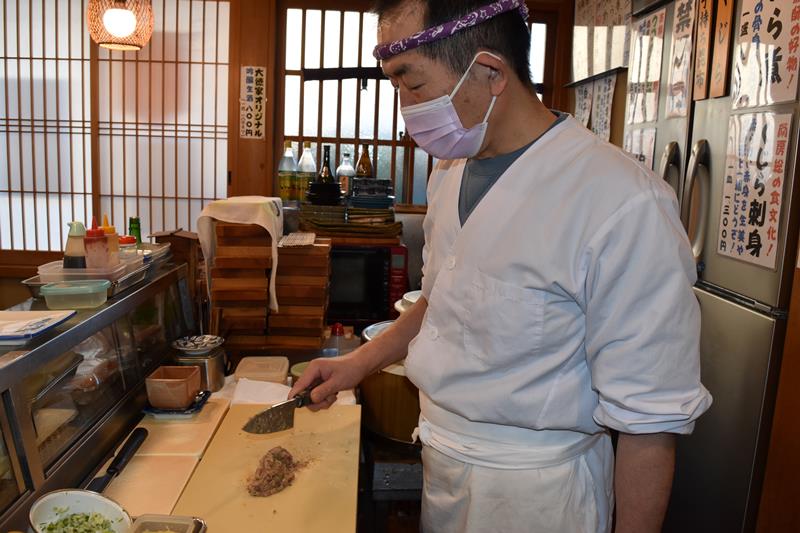 アジの上に具材をのせて、たたきながら混ぜる栗原さん