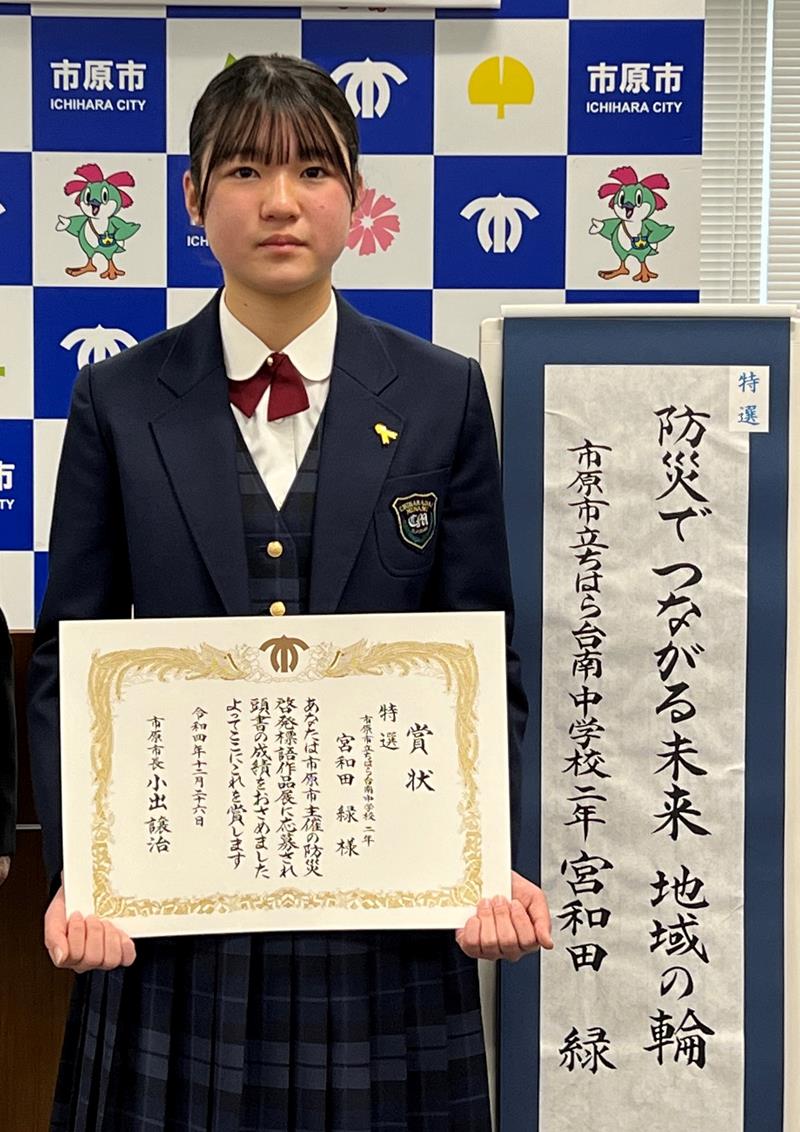 特選を受賞した防災啓発標語と並ぶ宮和田さん＝市原市役所