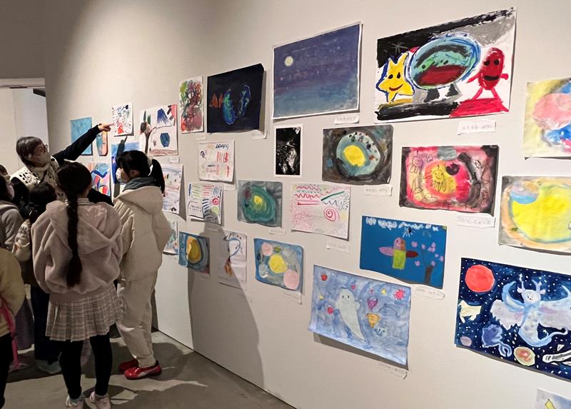 「子ども絵画展」で児童らと作品を鑑賞する鴻池さん（左奥）＝市原市の市原湖畔美術館
