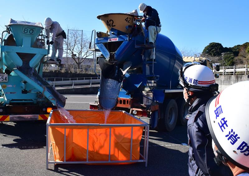 ミキサー車から簡易防火水槽に水を出す訓練参加者＝茂原市