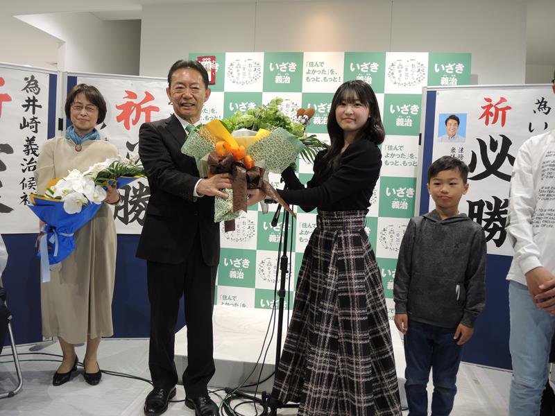 ６選を決め支援者から花束を渡される井崎氏＝２３日午後１０時５５分ごろ、流山市