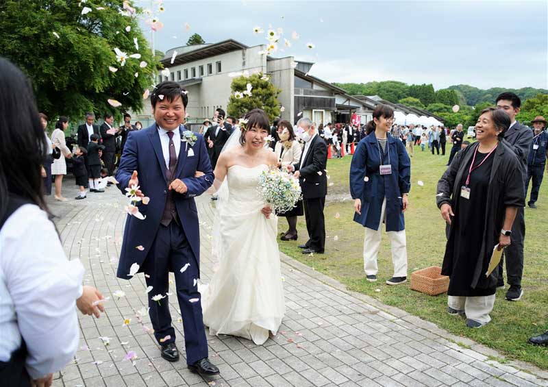旧老川小の校庭でフラワーシャワーで祝福される新郎新婦=大多喜町