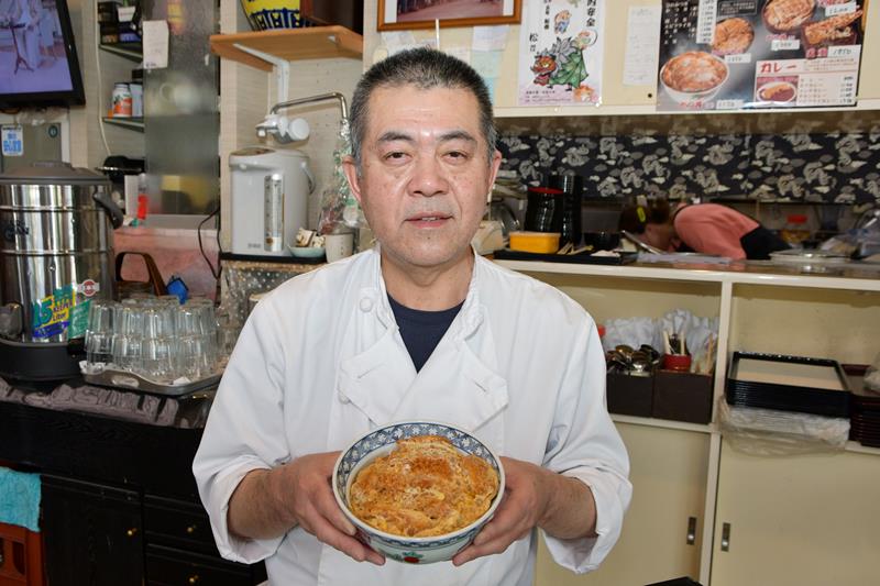 名物のカツ丼を手に持つ５代目の邦之さん＝香取市