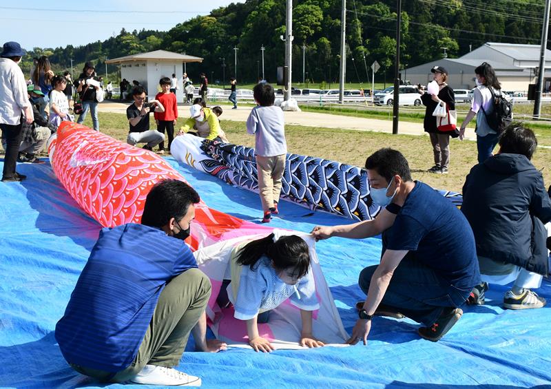 こいのぼりの中を元気にくぐる子どもたち＝香取市