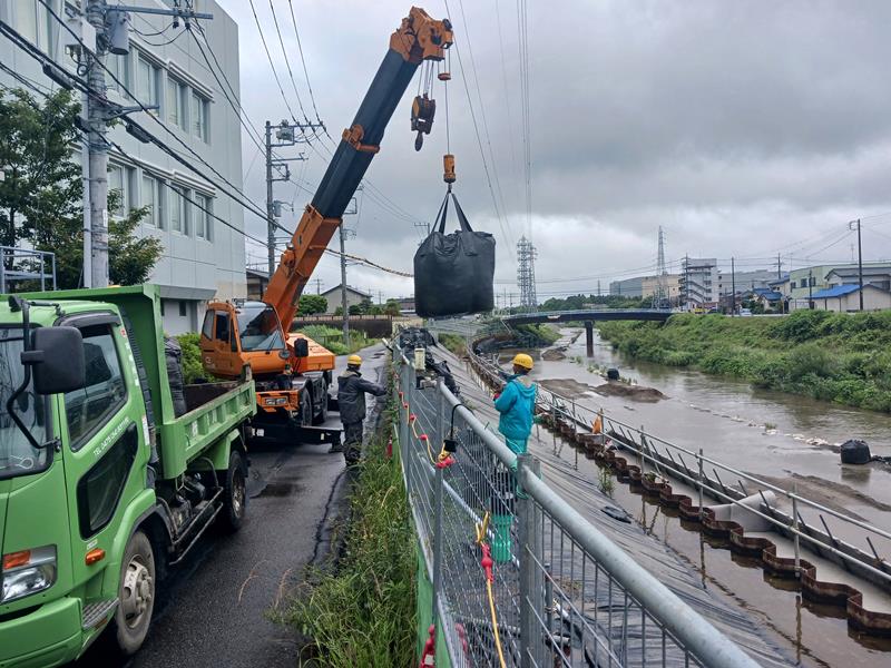 大雨の予報を受け、一宮川沿いに次々と設置される１トンの土のう＝２日午後、茂原市
