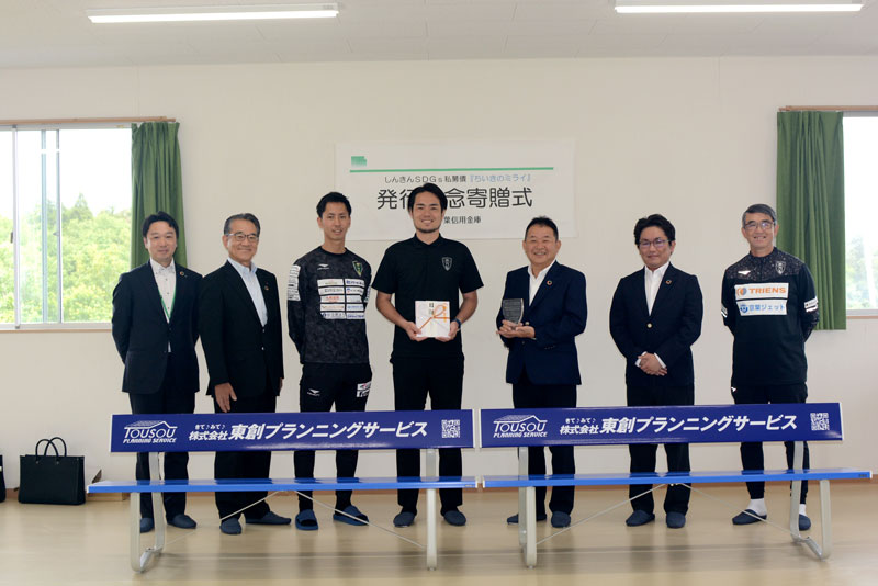 寄贈されたベンチの前で目録を持つ佐藤フロント（右から４人目）、横尾社長（同３人目）ら＝市原市