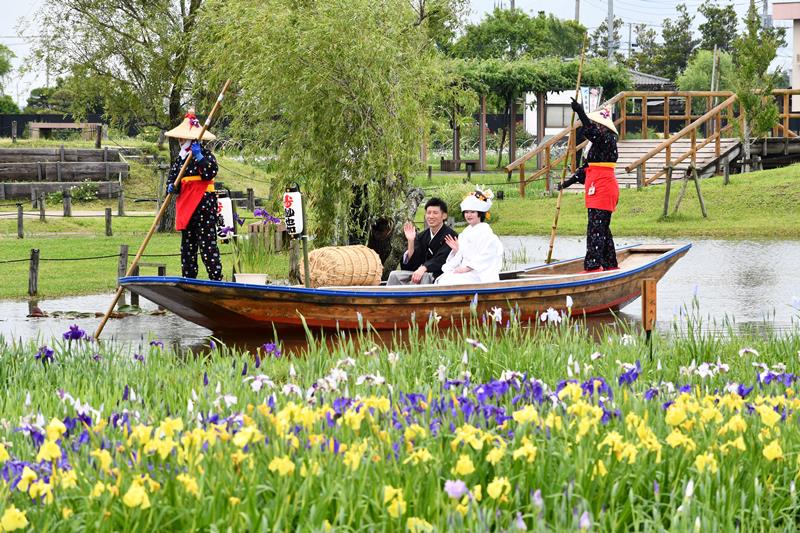 来園者から祝福を受けながら園内を舟で巡る新郎新婦＝３日、香取市の水郷佐原あやめパーク