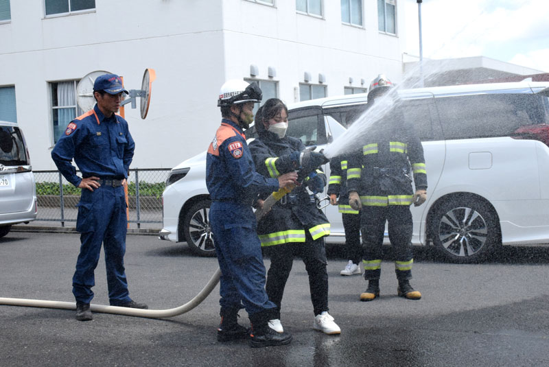 ホースに触れて放水を体験する参加者＝横芝光町