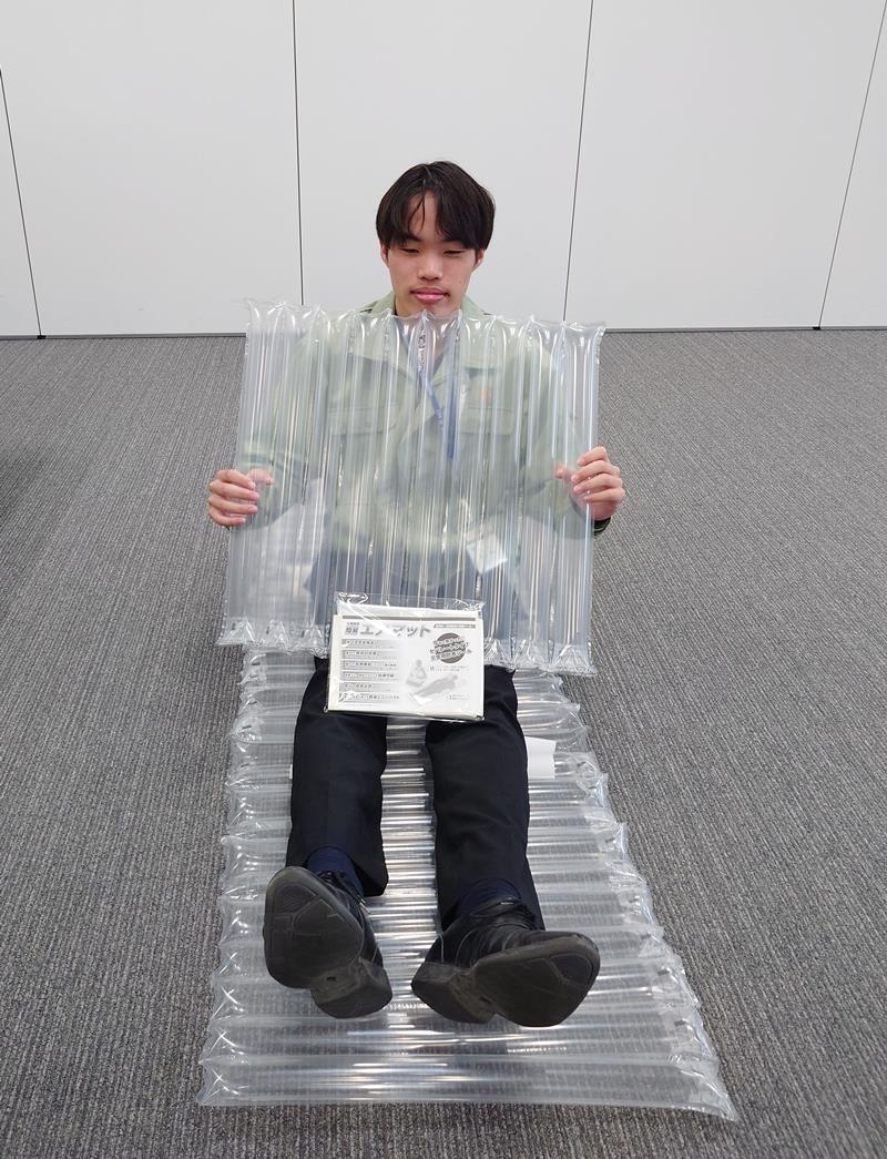 親和パッケージの緩衝材がエアマットとして使えることを実演する市原市職員＝同市役所