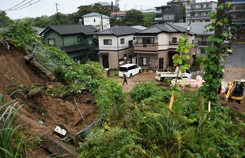 大雨の影響でのり面が崩れ、大量の土砂が住宅の手前まで押し寄せた＝８日午後３時３５分ごろ、成田市囲護台
