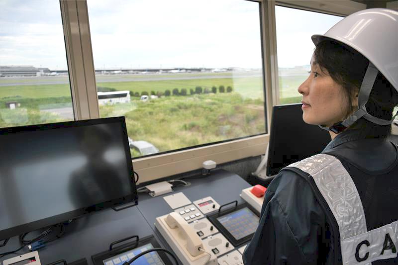 管制卓や電話回線などが備わった非常用管制塔から滑走路を目視する管制官=成田空港