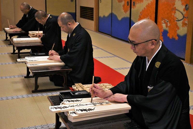 成田山新勝寺で正月準備の護摩札作りが始まり、思いを込めながら筆を入れる僧侶ら=15日、成田市