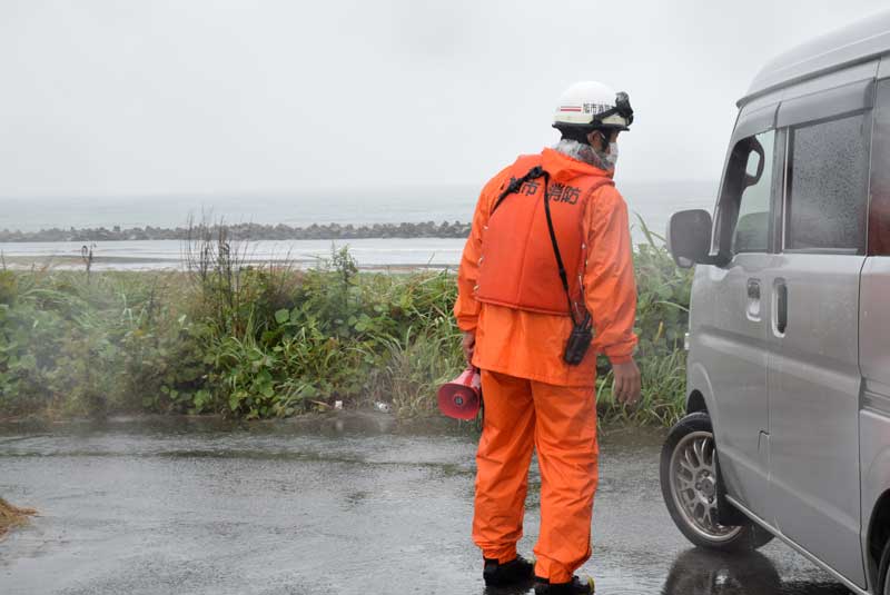 海岸堤防付近に来た車に避難指示の発令などを伝える消防隊員＝９日午前９時４５分ごろ、旭市