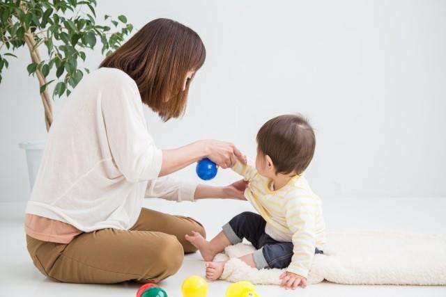 子どもの服を着替えさせる母親（写真はイメージ）